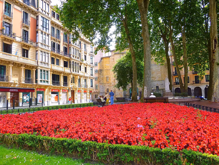 Rote Blumenbeete und Bäume im Albia-Garten, Bilbao