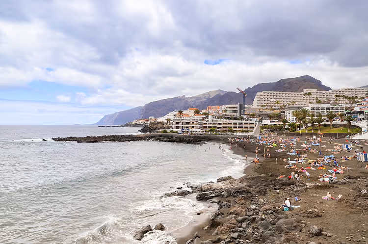 Svart sandstrand mot klippene på Tenerife