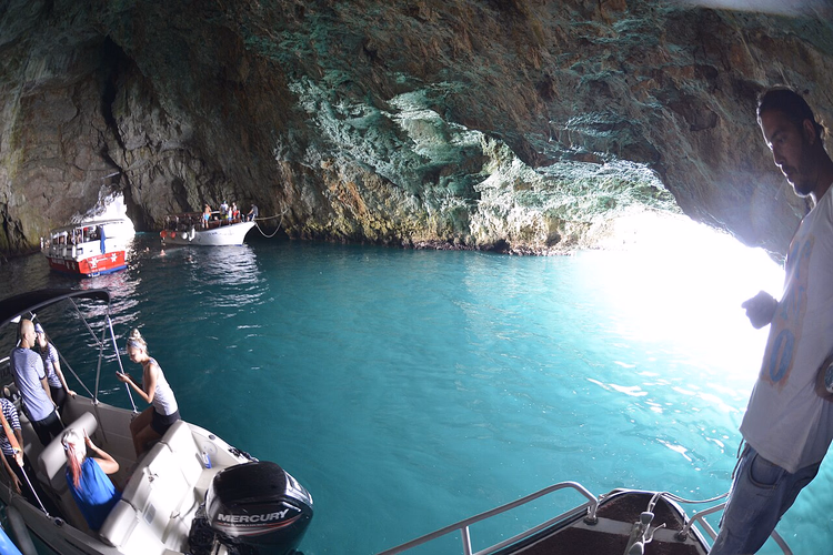 Boten met toeristen in het turquoise water van de grot