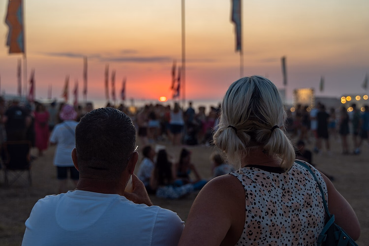 Festivalmenge mit Fahnen bei Sonnenuntergang