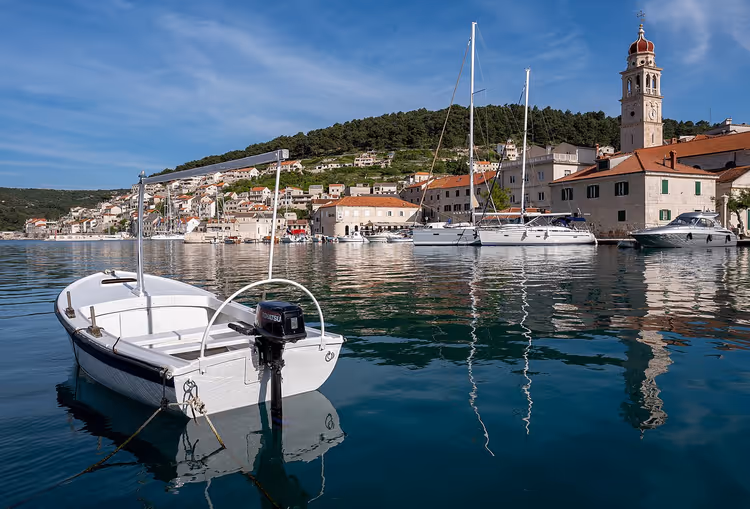Pučišća limanında arka planda kiliseyle tekne