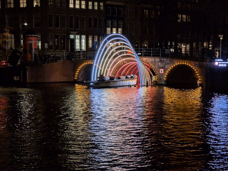 Barca che passa attraverso un arco illuminato su un canale