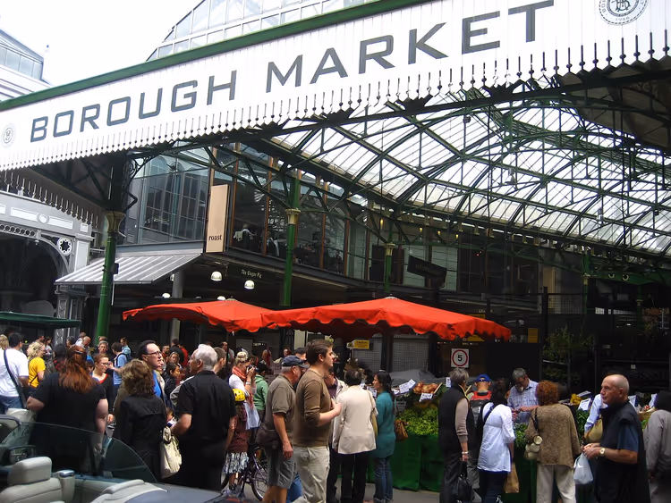 Alışveriş yapanlarla pazar koridorlarının üzerindeki Borough Market tabelası