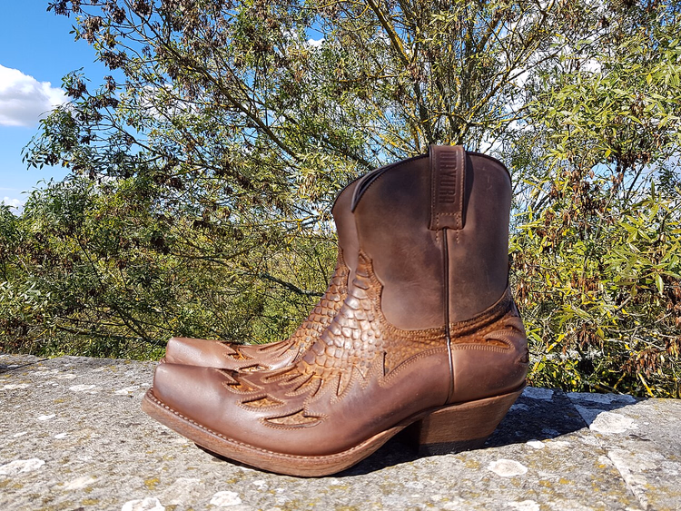 Bruine handgemaakte leren enkelboots op een steen