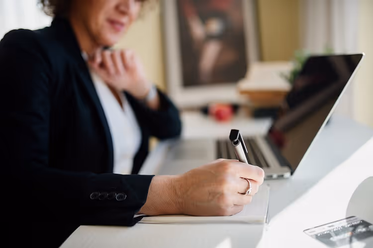 امرأة ببدلة عمل تدوّن الملاحظات بقلم