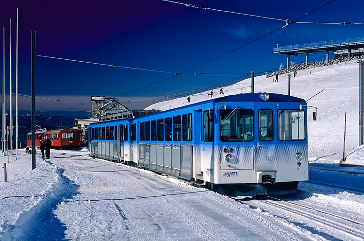 Blått tog på den snødekte stasjonen Rigi Kulm