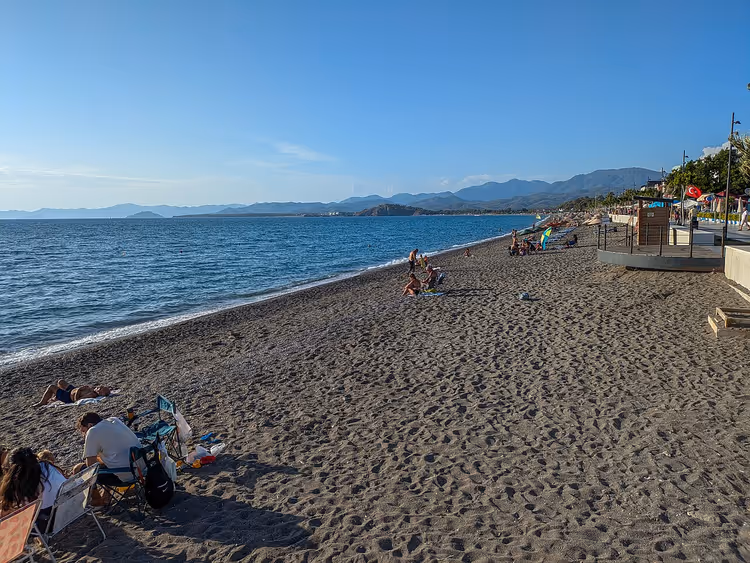 Calis-stranden med badende og fjell i det fjerne