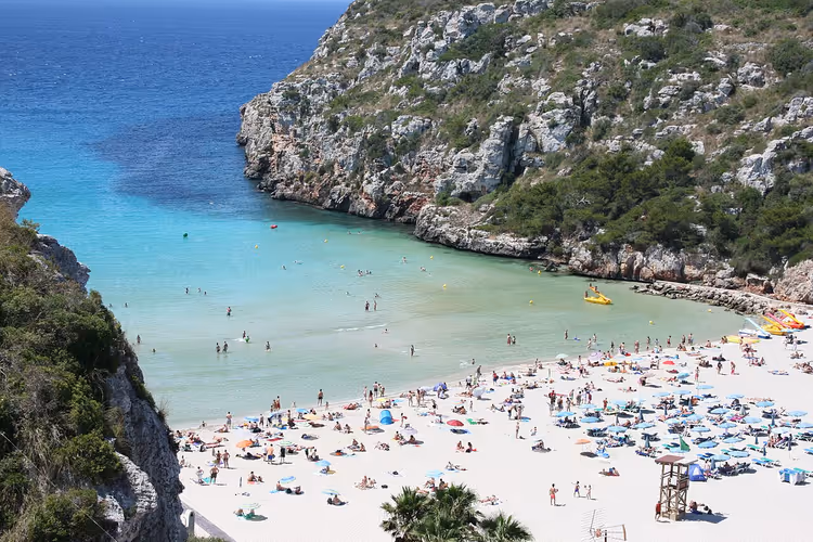 Strand in een baai met turquoise water en kliffen