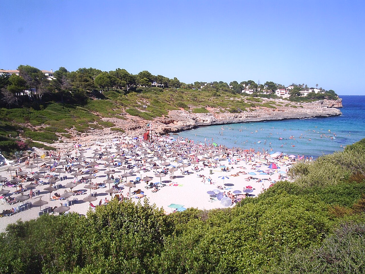 Cala Mandia-viken med parasoller og turkisblått vann