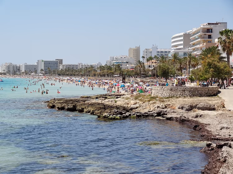 Strand van Cala Millor met hotels, palmbomen en badgasten