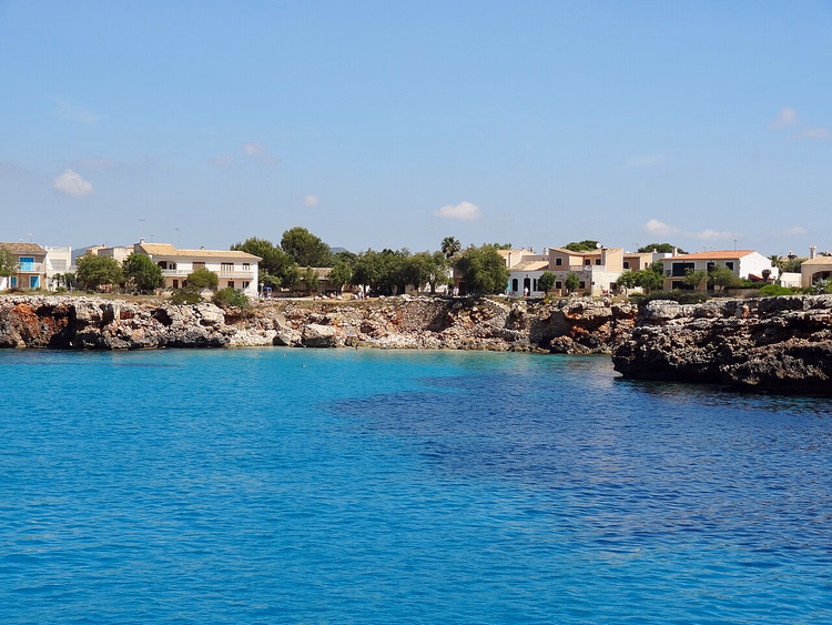 Türkisfarbenes Wasser der Bucht von Cala Morlanda an der felsigen Küste
