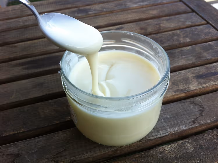 Smeltkaas in een pot, lepel trekt de kaasmassa