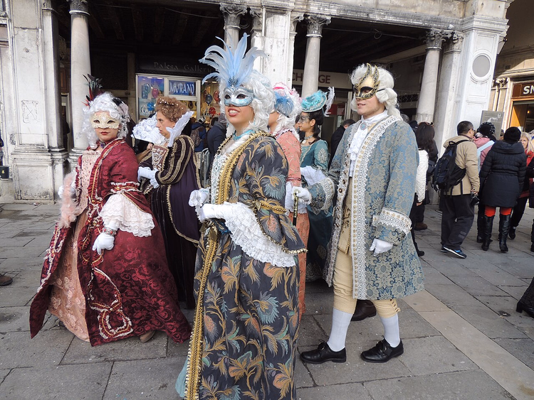 Gemaskerde carnavalsdeelnemers onder de arcades van San Marco