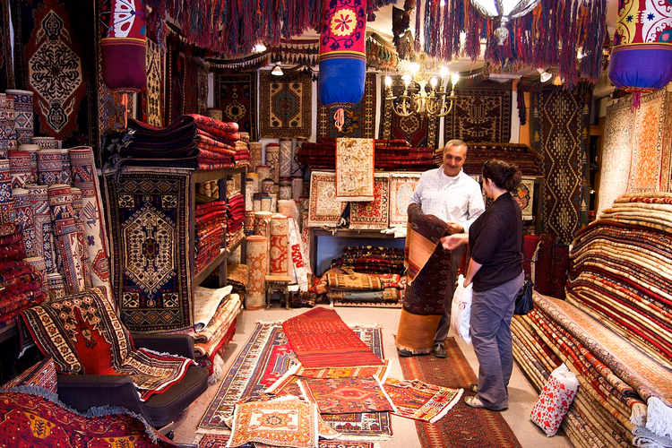 Selger som viser et teppe til en kunde i en butikk i Ankara