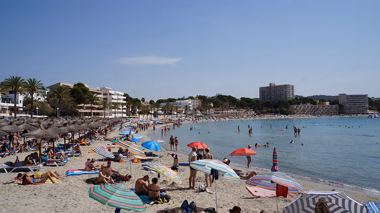 Strand med parasoller og feriegjester ved havet
