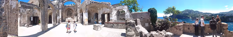 Ruiner av Castello Aragonese med turister og havutsikt