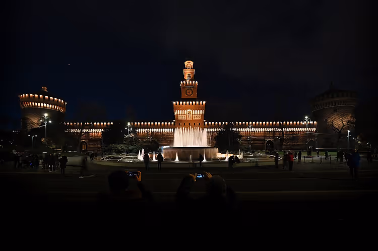 Castello Sforzesco om kvelden med en fontene på plassen