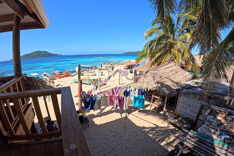 Utsikt fra terrassen mot en strand med klesvask og palmer