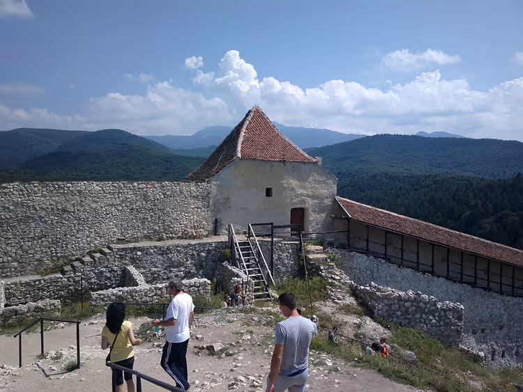 Туристы у каменной крепости с башней и горами