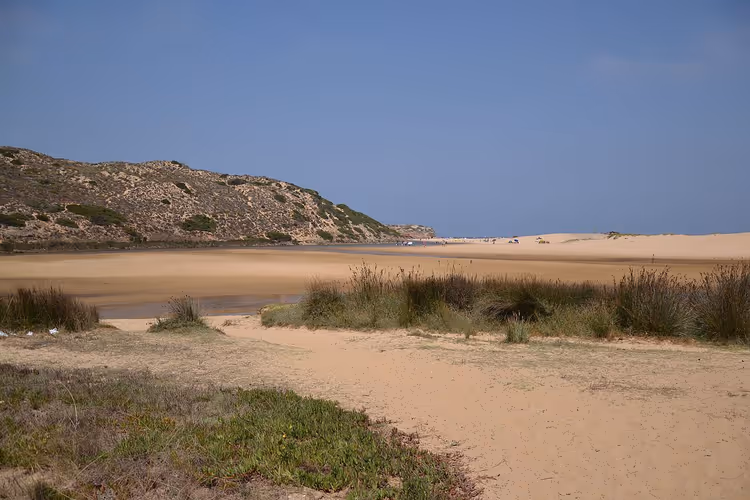 Sandstrand an einer Flussmündung zwischen Hügeln
