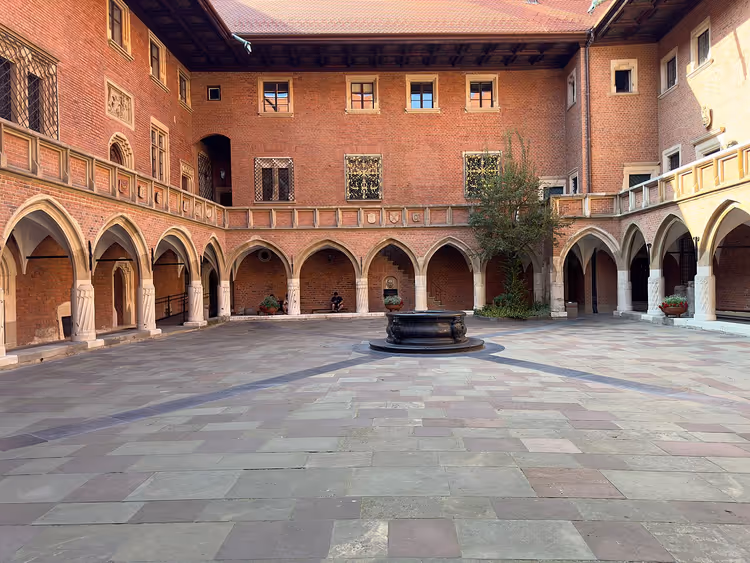 Binnenplaats van het Collegium Maius met arcaden en een put in Krakau