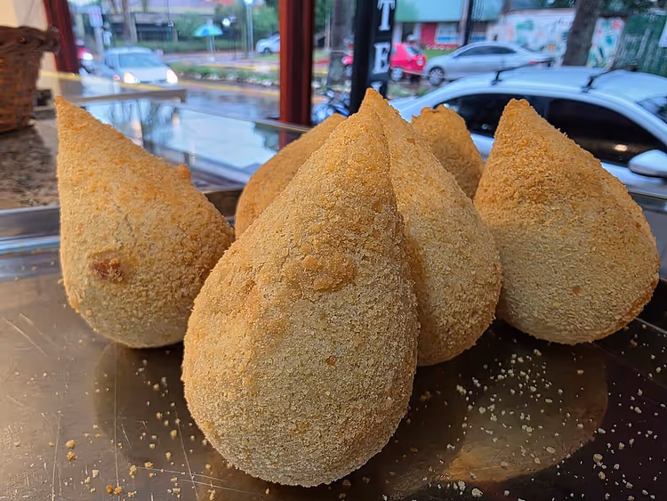 Vitrindeki tepside coxinha, arka planda sokak