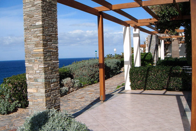 Pergola met een stenen zuil op een terras aan zee