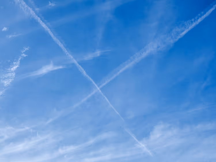 Kryssende flykontrailer på en blå himmel