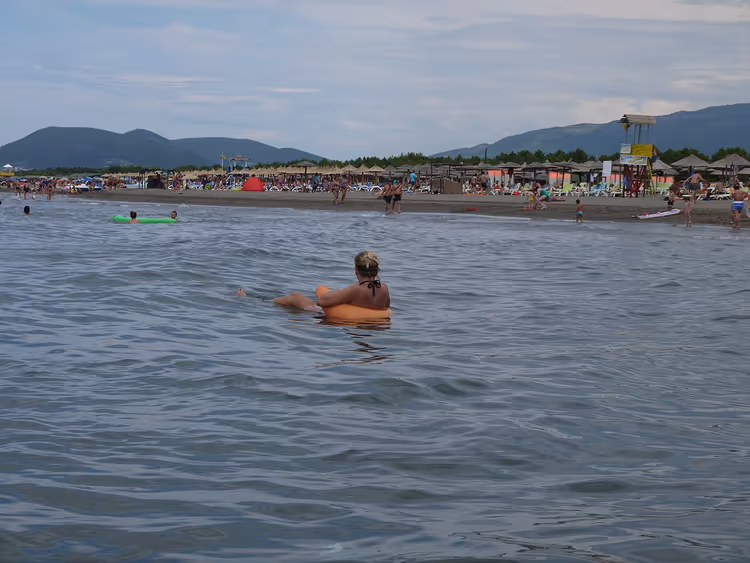 Badende im flachen Wasser eines breiten Sandstrands
