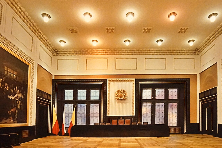 Ceremoniële zaal van het stadhuis met een schilderij en vlaggen