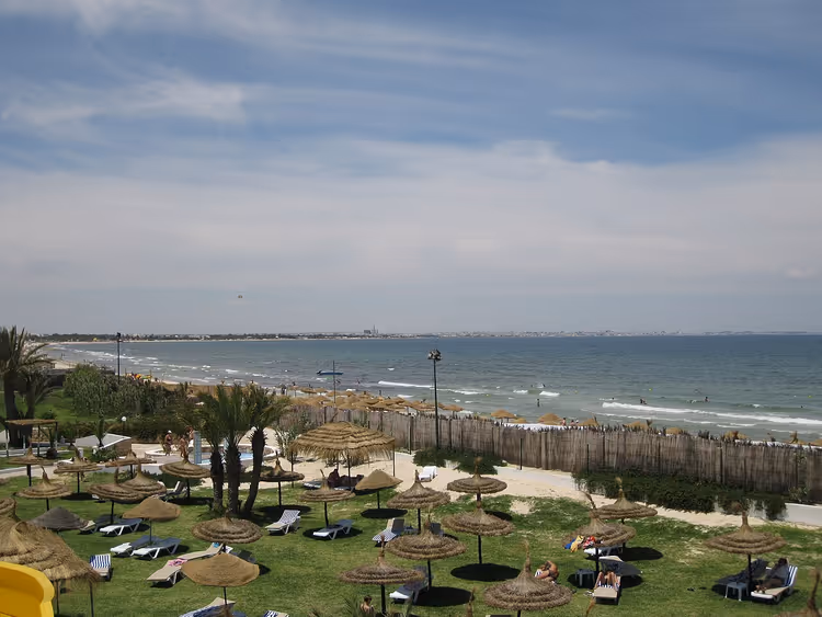Deniz kenarında şemsiyeler ve şezlonglarla plaj