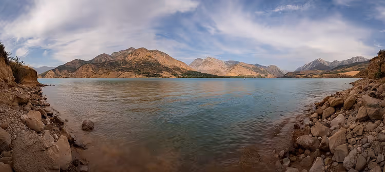 Dağlar ve kayalık kıyısıyla Charvak Baraj Gölü panoraması