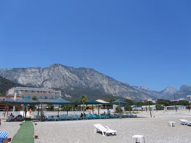 Dağlara karşı şezlonglar ve şemsiyelerle plaj