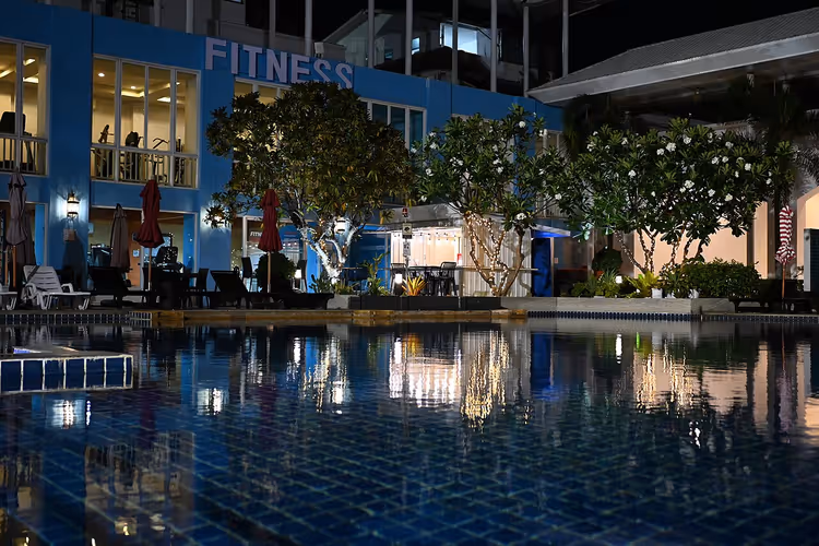 Nachtelijk hotelzwembad in Pattaya met een FITNESS-bord