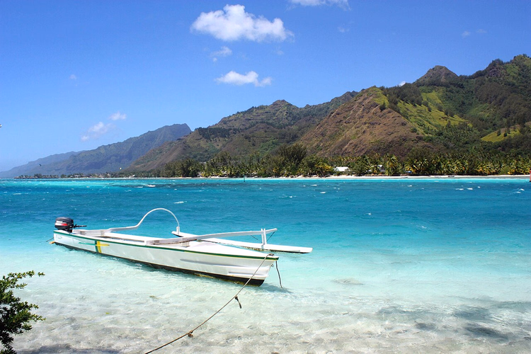 Klar lagune på Moorea med en båt nær fjellene
