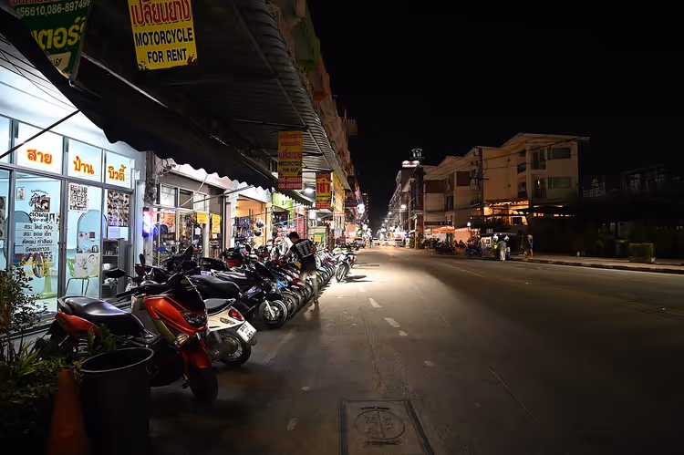 Tayland'da gece bir dükkânın önünde sıralanmış scooterlar
