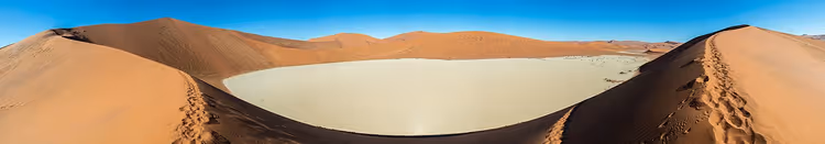 Namib Çölü'nün kızıl kumulları arasındaki beyaz Deadvlei düzlüğü