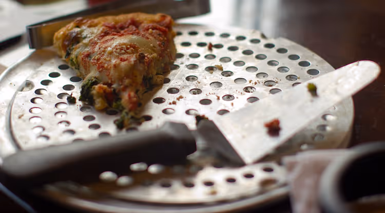 Puntje deep-dish pizza op een geperforeerde pan