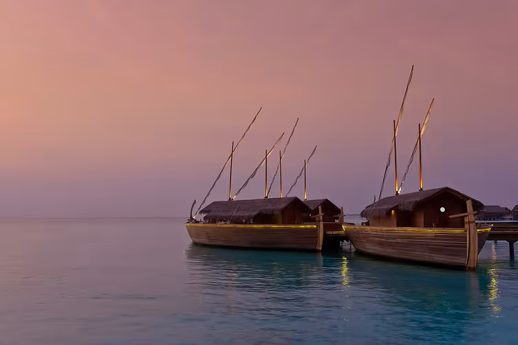 قوارب دوني مالديفية تقليدية على الماء عند الغروب