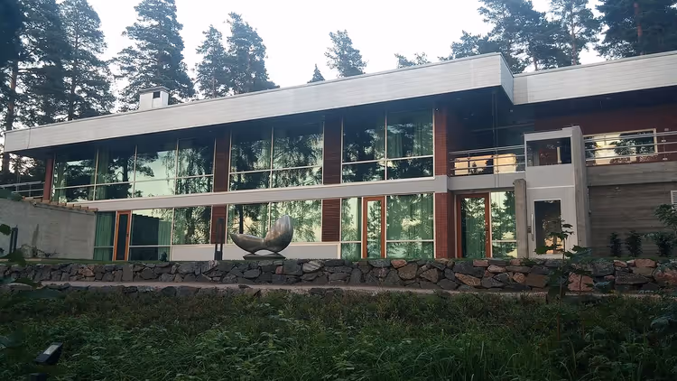 Glassbygningen til Didrichsen kunstmuseum blant furutrær