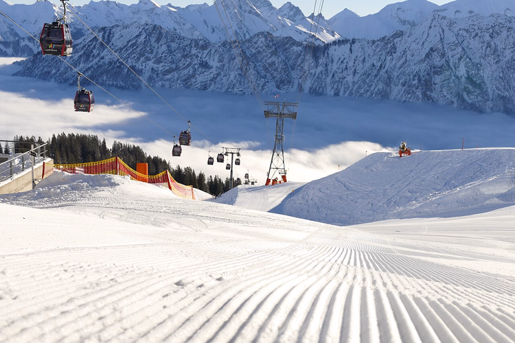Gondeln der Fellhornbahn über einer präparierten Piste im Winter