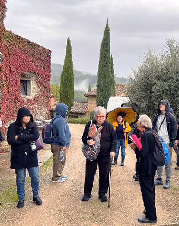 Turisti in tour in un borgo toscano tra i cipressi