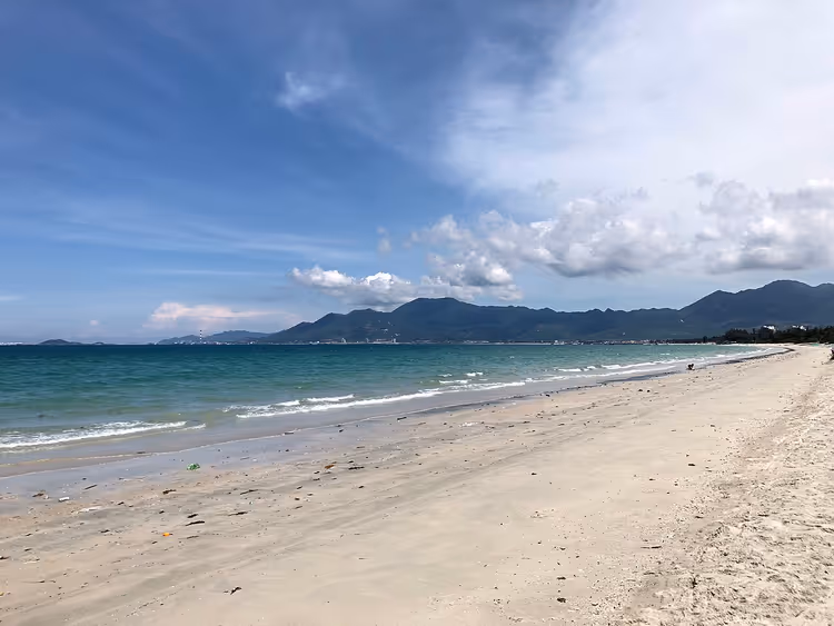 Sandstrand med hav og fjell i det fjerne