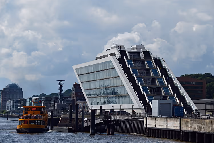 Hjørnebygget Dockland i glass ved vannet med en ferge