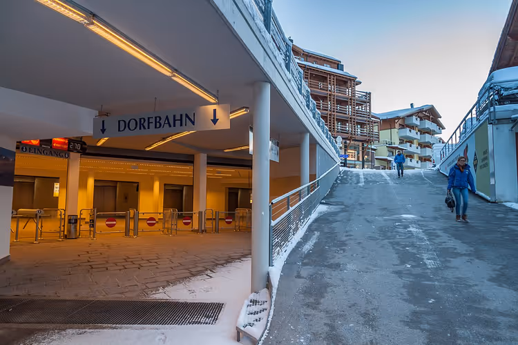 Ingang van het station van de Dorfbahn met bord en mensen