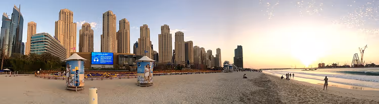 Panorama av Dubai Marina-stranden med skyskrapere ved solnedgang