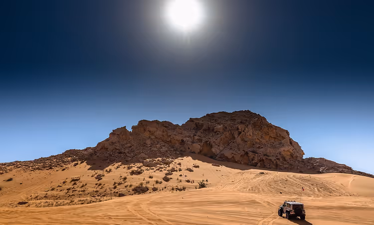 Woestijnlandschap met een zandstenen rotsformatie en een offroadvoertuig
