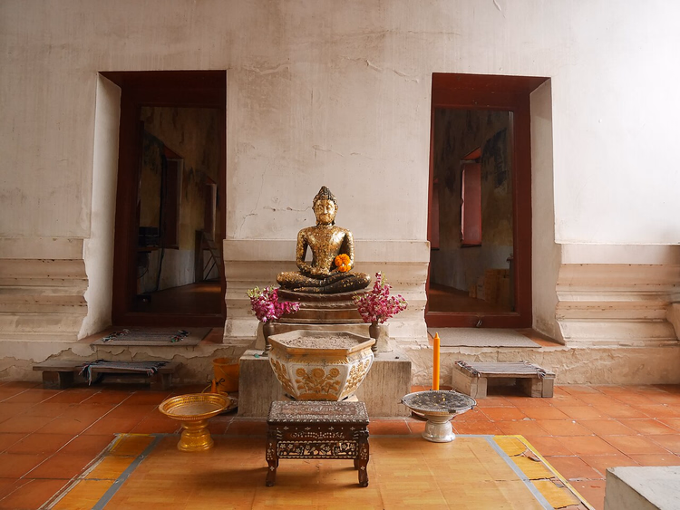 Buddhastatue ved veggen i en gammel ubosot
