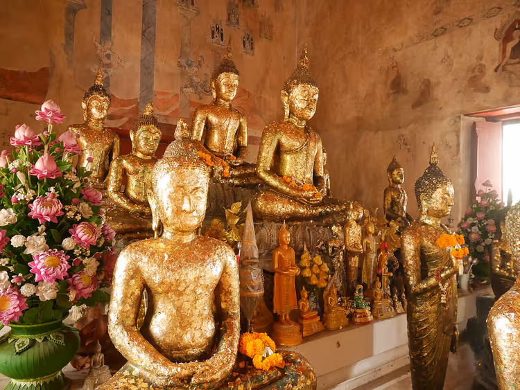 Forgylte Buddhastatuer inne i et thailandsk tempel