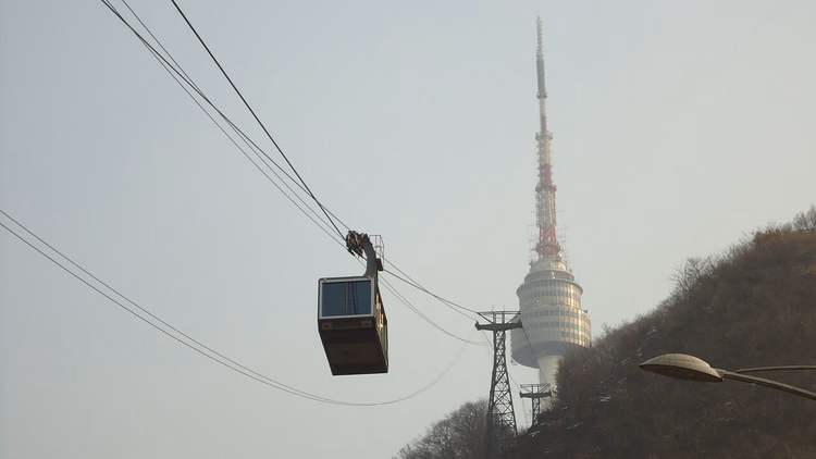 Arka planda Namsan Kulesi ile teleferik kabini